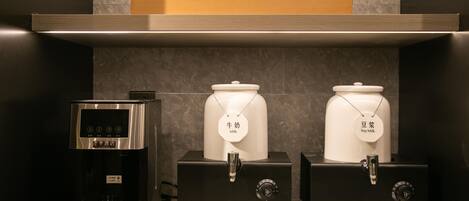 A coffee machine and two milk dispensers in a hotel setting.