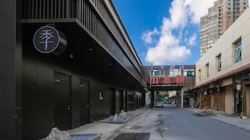 A modern building with a prominent sign, a clear sky, and a street leading to a traditional building.
