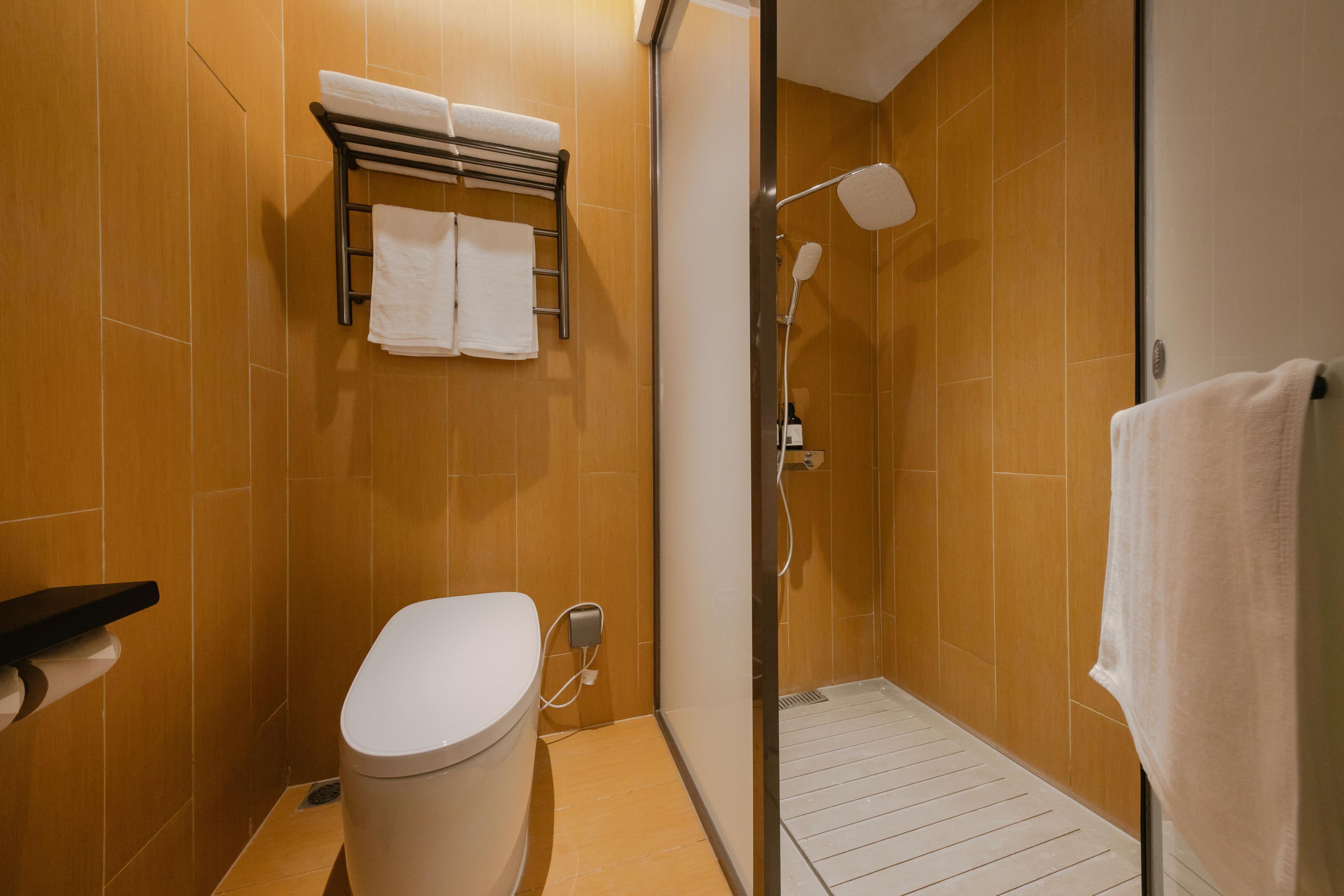 A bathroom with a toilet, a towel rack, and a shower.