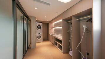 A modern laundry room with built-in appliances, a sink, and a vacuum cleaner.