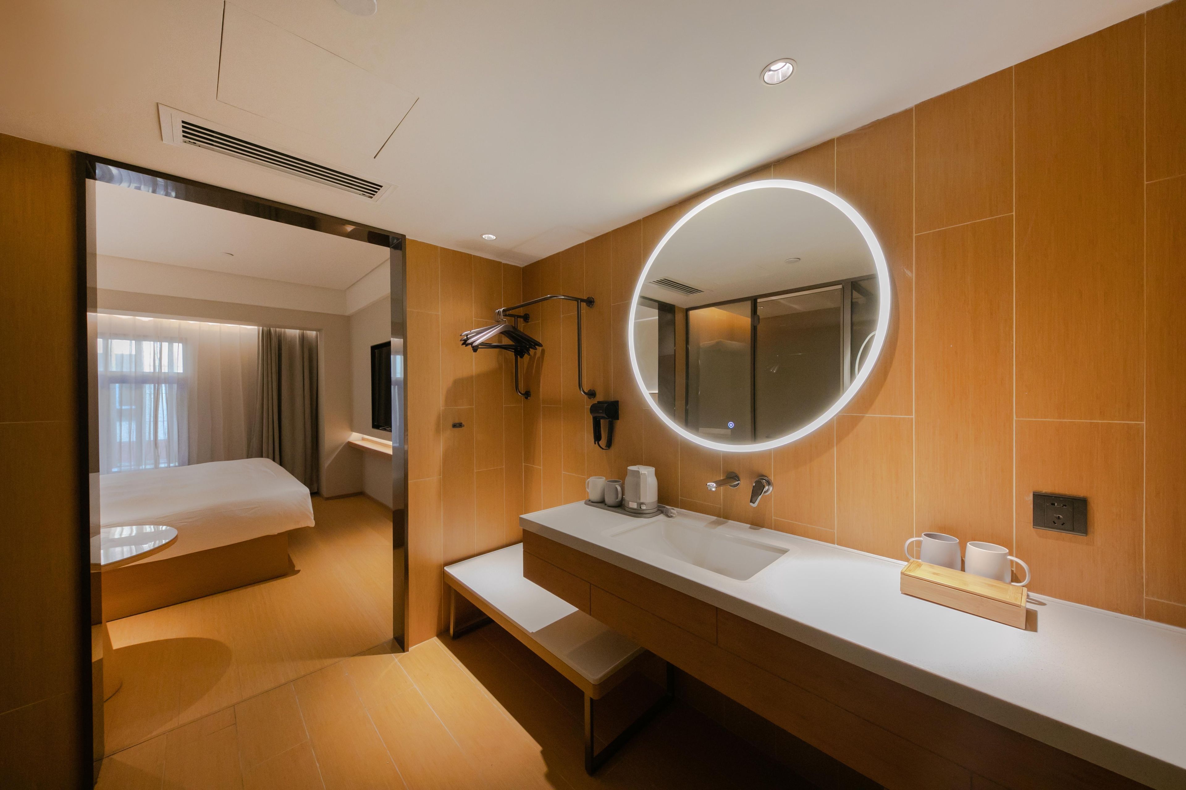 Un baño de hotel con un espejo grande, un lavabo y una zona de ducha.