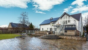 A house with a stone patio, a metal fence, and a solar panel on the roof. - Charming gite in Waimes near Spa-Francorchamps (Waimes)