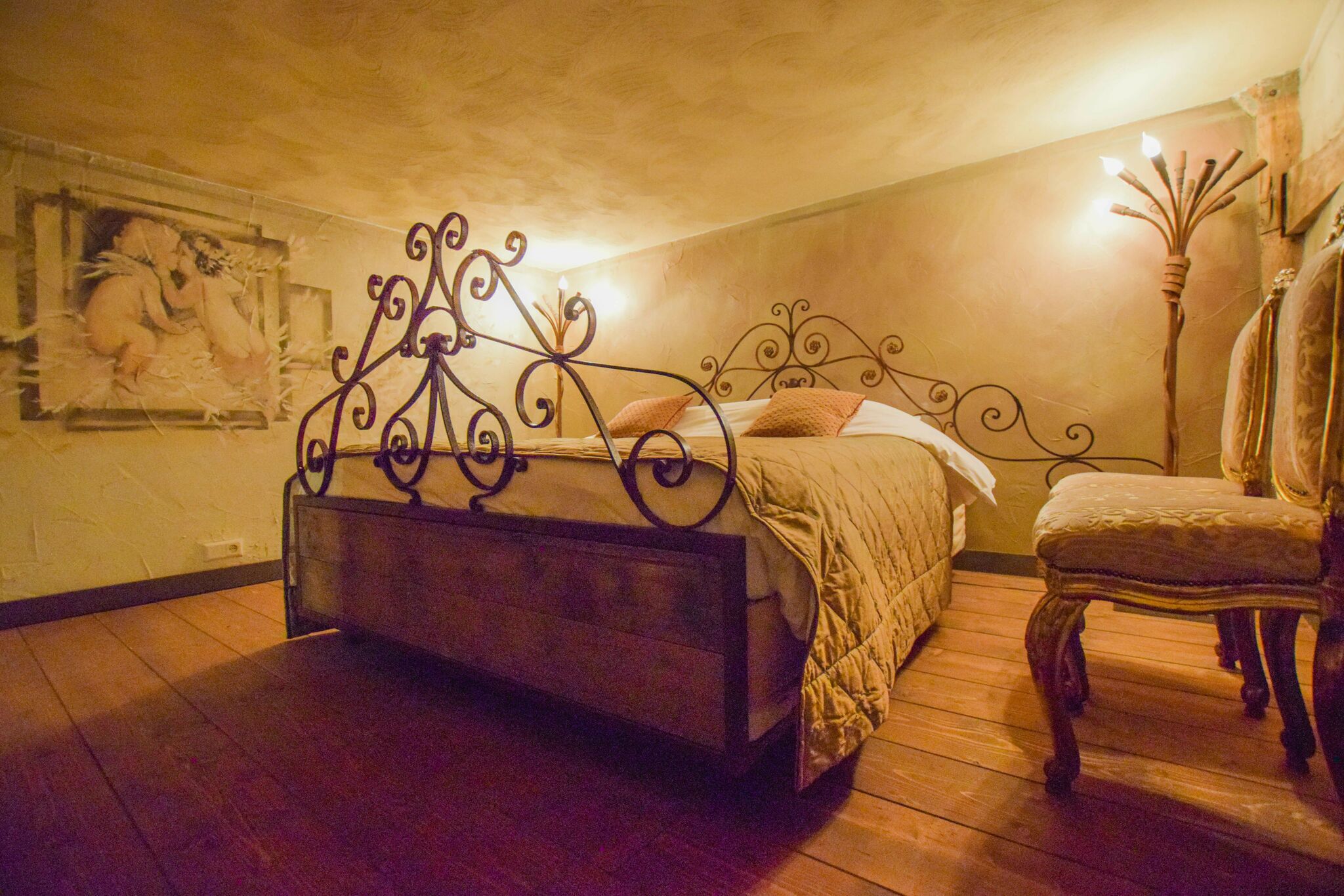 A bedroom with a metal bed frame, a wooden bench, and a wall-mounted lamp.