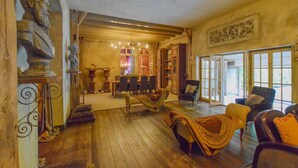 Una habitación amplia con suelo de madera, un comedor con mesa y sillas, y una zona de estar con sofás y sillones.