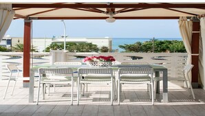 A covered outdoor seating area with a table and chairs, overlooking a pool and the sea. - Alcamo Marina Villa | Pool (Alcamo Marina)