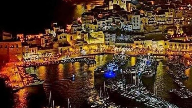 A nighttime view of a historic town with buildings along a waterfront, illuminated by artificial lights. - Alcamo Marina Villa | Pool (Alcamo Marina)