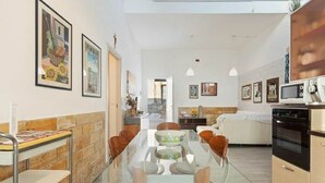 A modern kitchen with a glass dining table, wooden chairs, and a built-in oven. - Alcamo Marina Villa | Pool (Alcamo Marina)