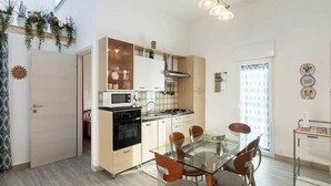 A modern kitchen with a glass dining table and chairs, a microwave, oven, and a sink. - Alcamo Marina Villa | Pool (Alcamo Marina)