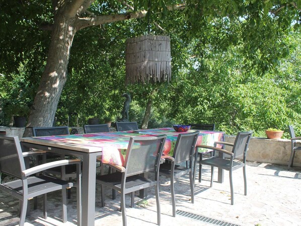 Un área de comedor al aire libre con mesa y sillas, rodeada de árboles.