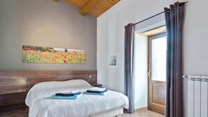 Ein Schlafzimmer mit einem Bett, einem Gemälde, einem Heizkörper und einer Tür mit Vorhängen.
