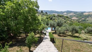 A stone staircase leading to a building with a view of rolling hills and trees.