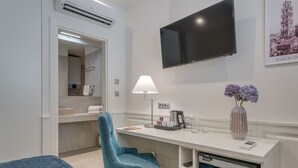 A modern hotel room with a bed, a desk with a lamp, a TV, and a vase with flowers. - Stonemasons Heritage (Split)