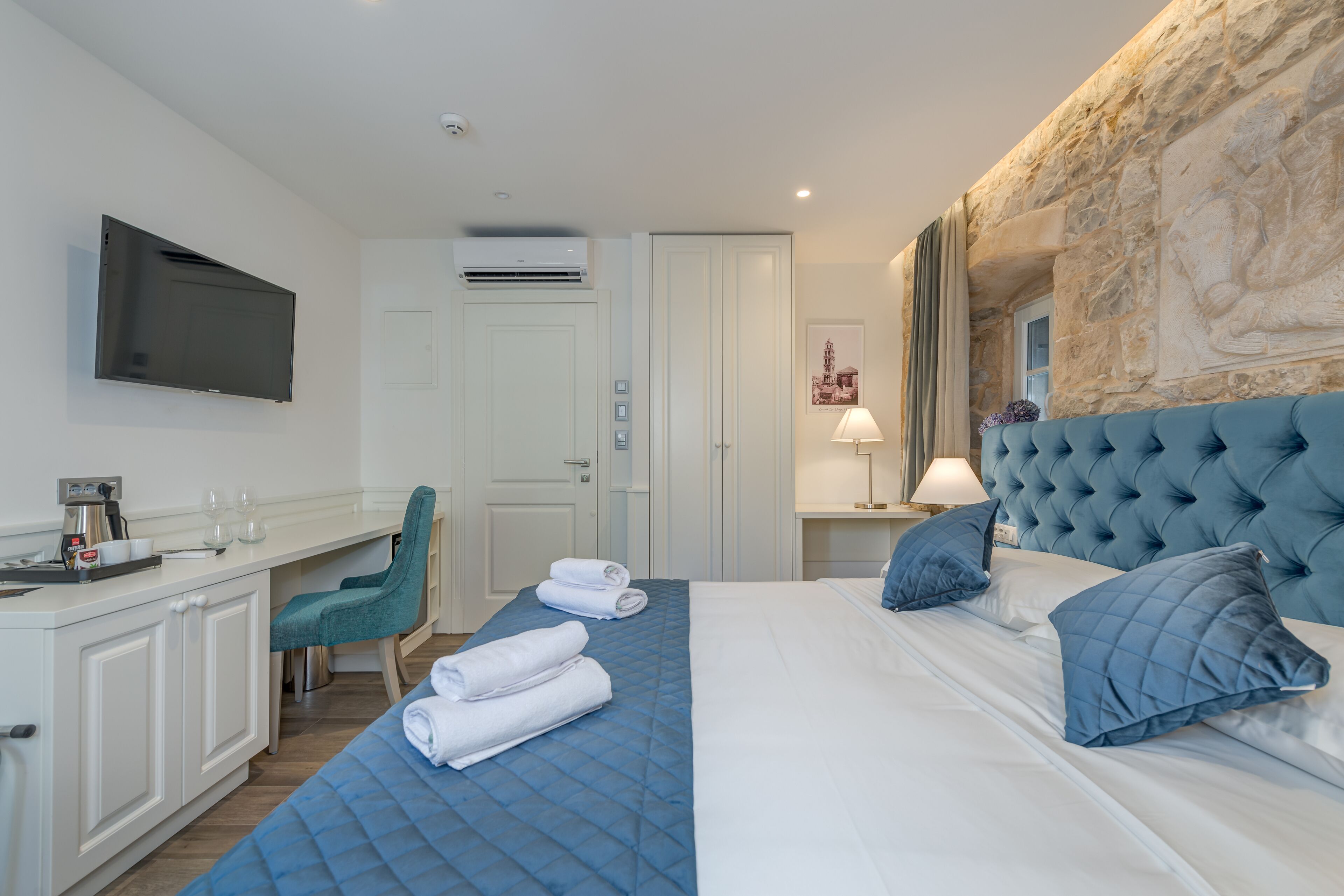 Habitación de hotel con cama, escritorio, silla y televisión en la pared.