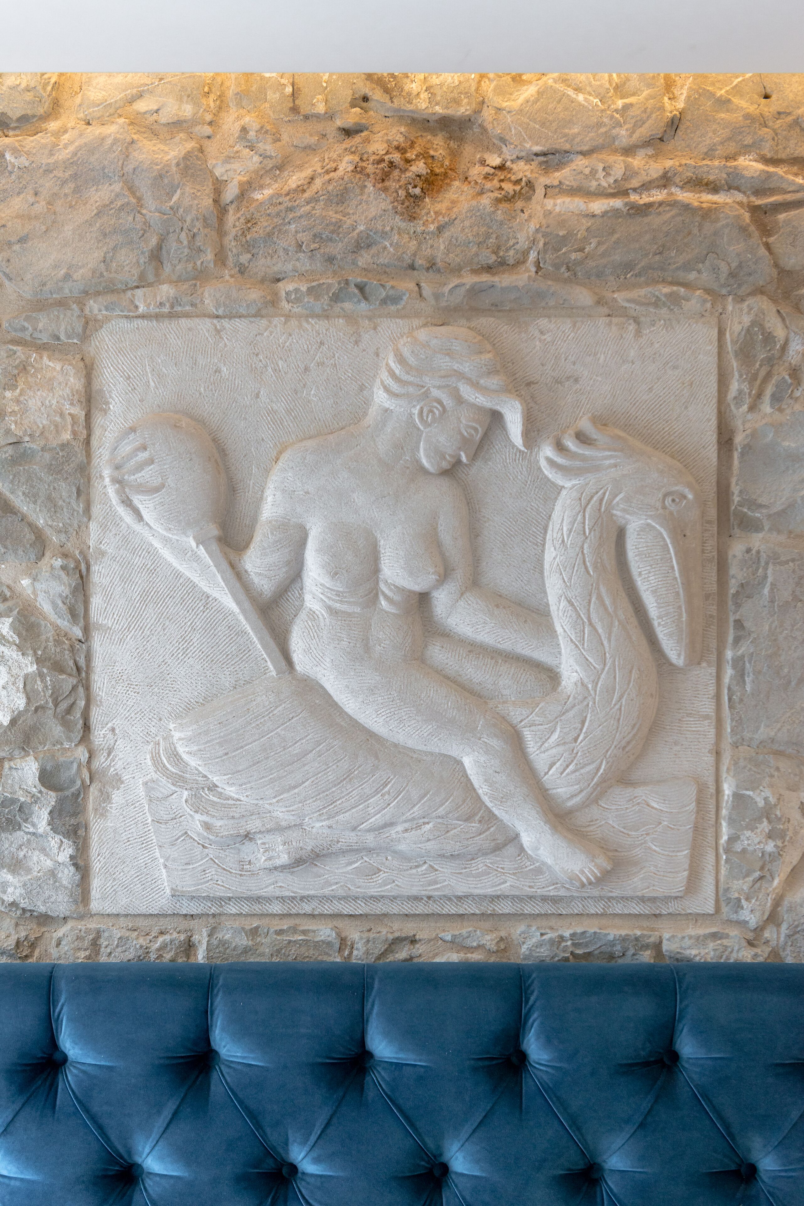 A stone wall with a relief sculpture of a figure holding a fish.