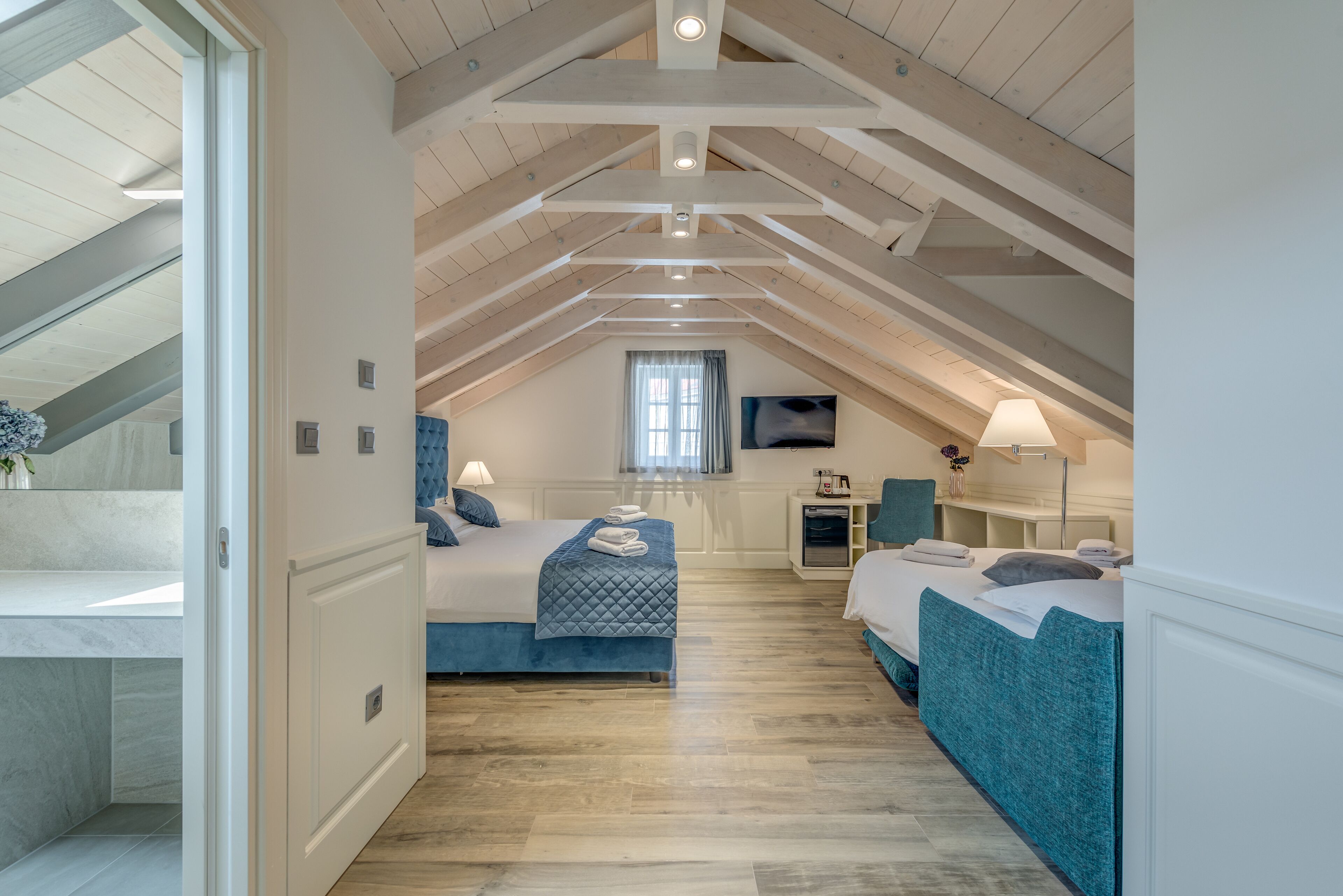 A bedroom with two beds, a window, a TV, and a lamp.