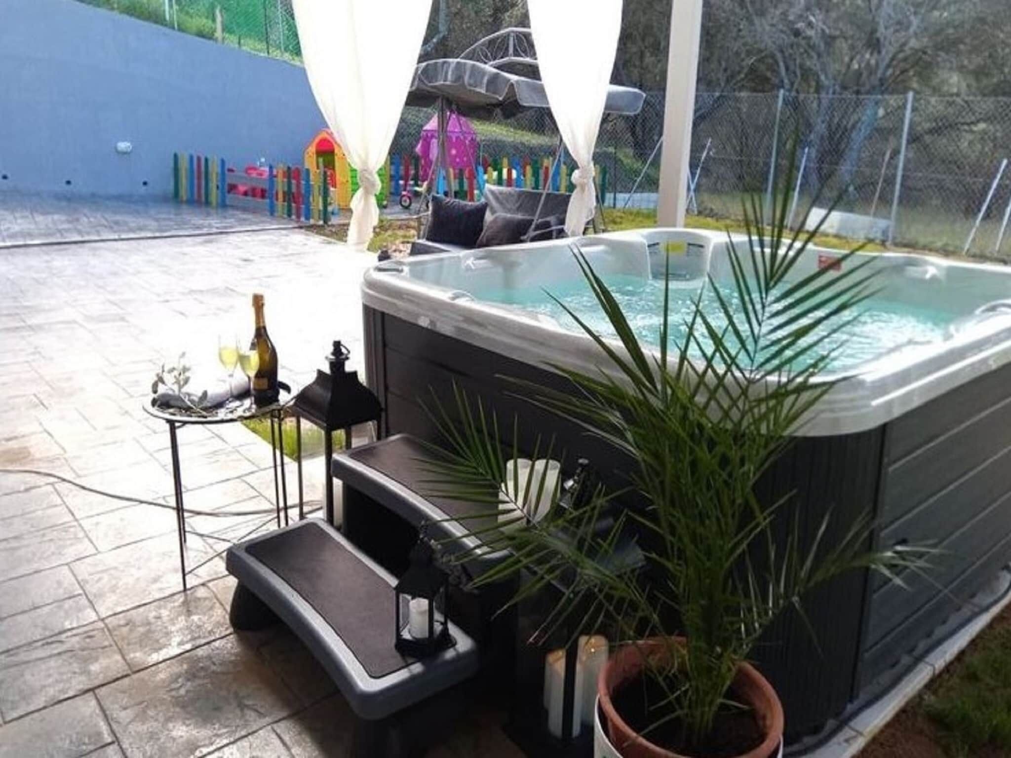 A hot tub with a step and a small table with a bottle and a candle.