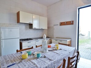 Een koelkast, een oven, een kookplaat, kookgerei, borden en bestek