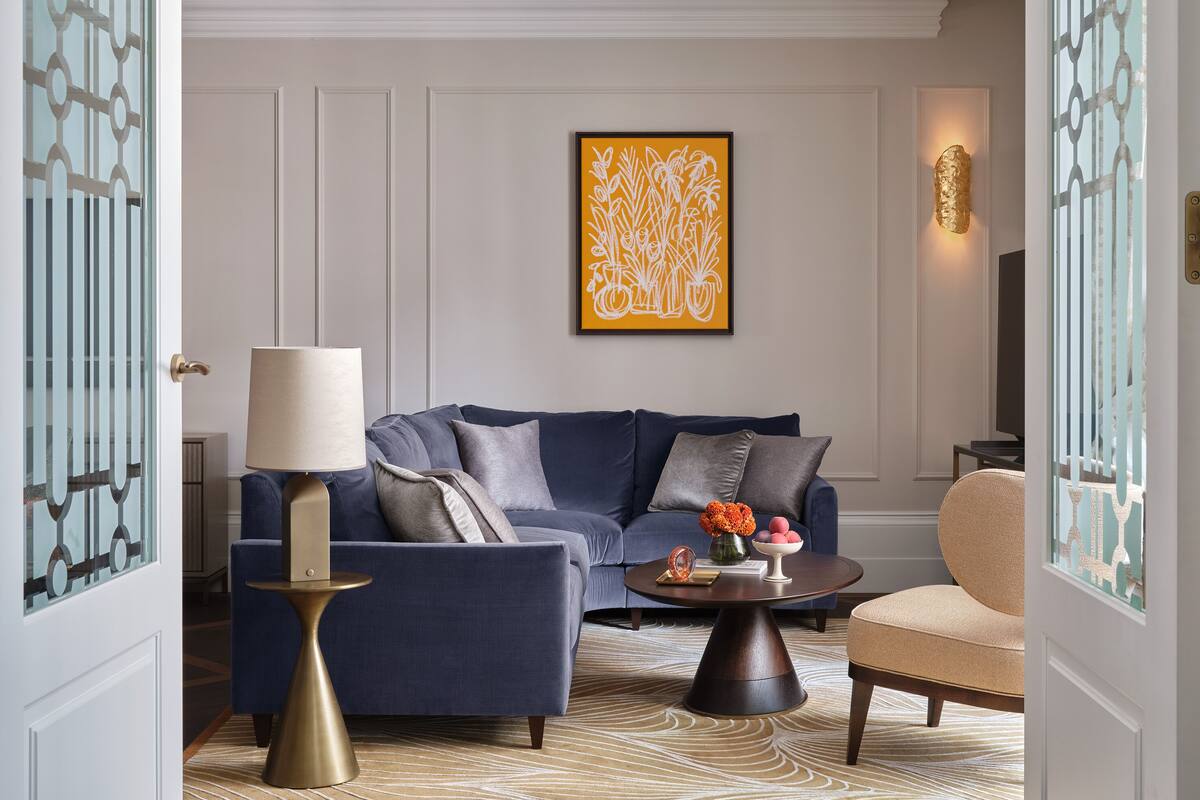 A modern living room with a blue sofa, a round coffee table, and a decorative lamp.