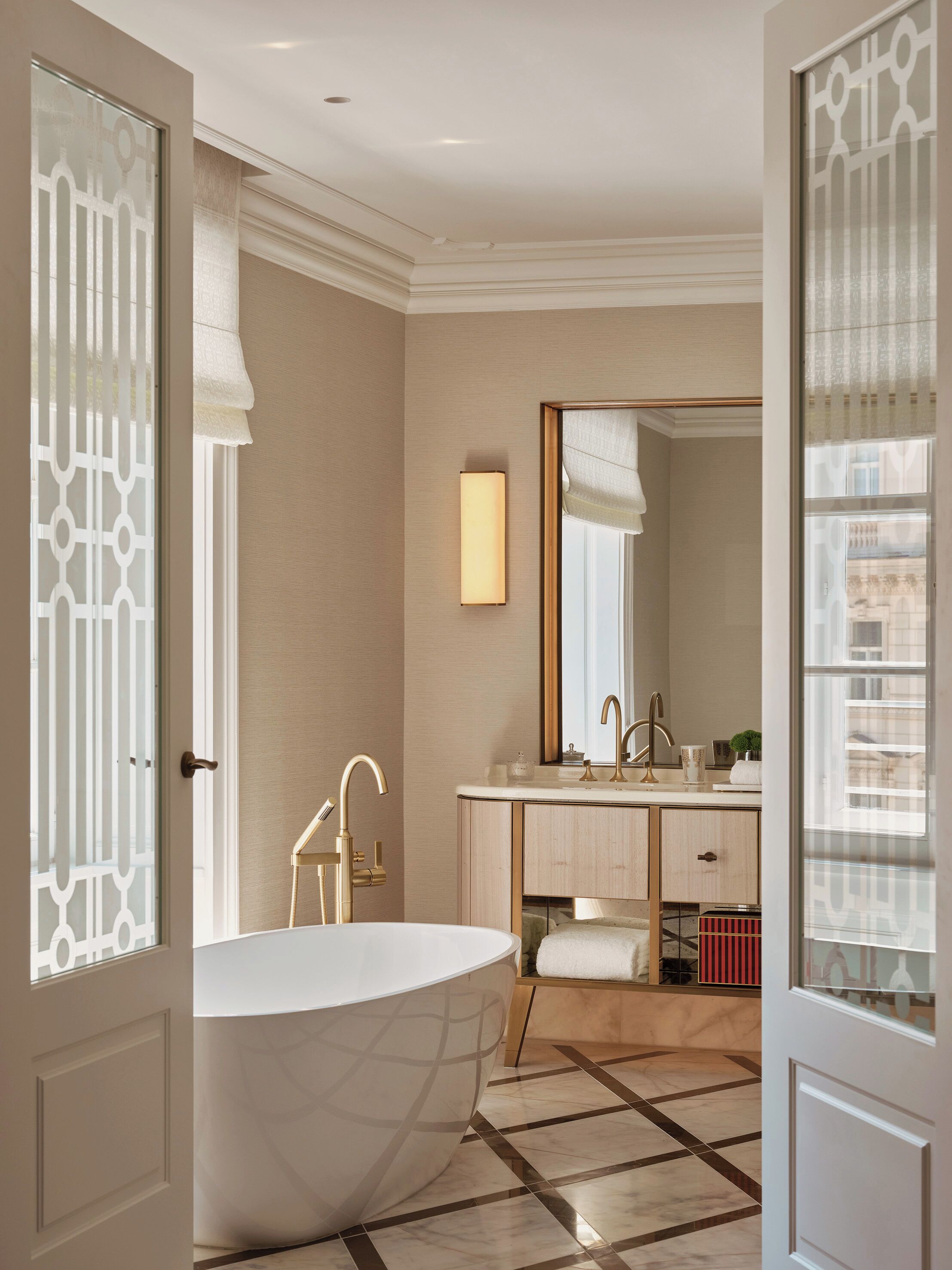 A bathroom with a freestanding bathtub, a vanity with a mirror, and a tiled floor.