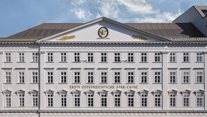 A large, white building with a classical facade, featuring a central entrance with a decorative arch and a wreath above it. - Rosewood Vienna (Vienna)