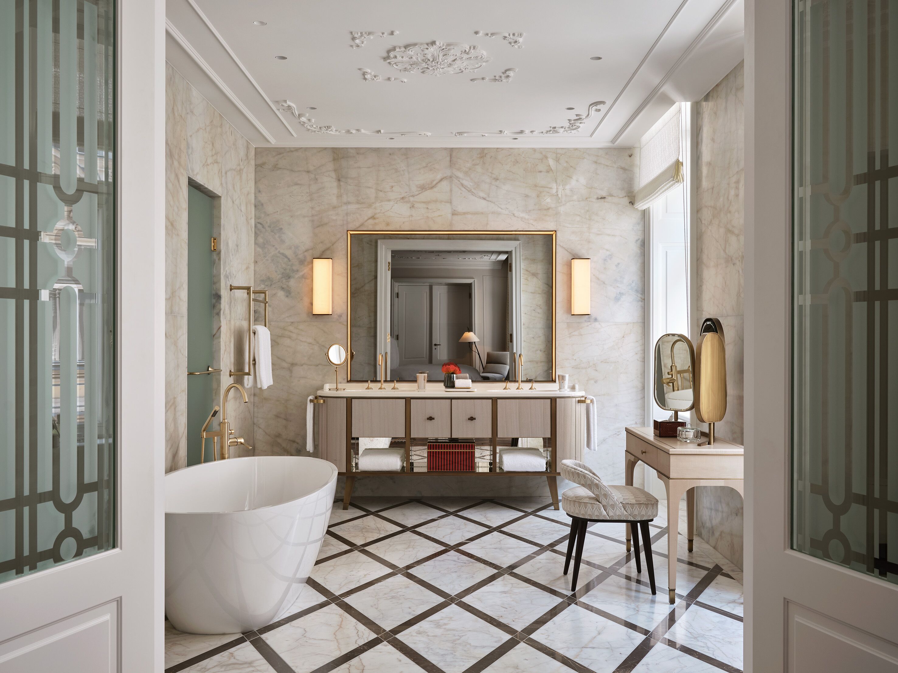 A luxurious bathroom with a freestanding bathtub, a large mirror, and a vanity with a double sink.