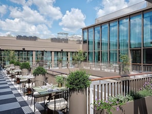 A rooftop terrace with outdoor seating and a view of a modern building. - Rosewood Vienna (Vienna)