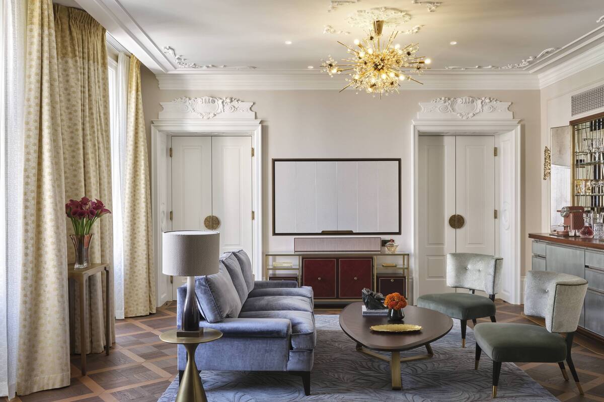 A living room with a sofa, armchairs, a coffee table, and a chandelier.