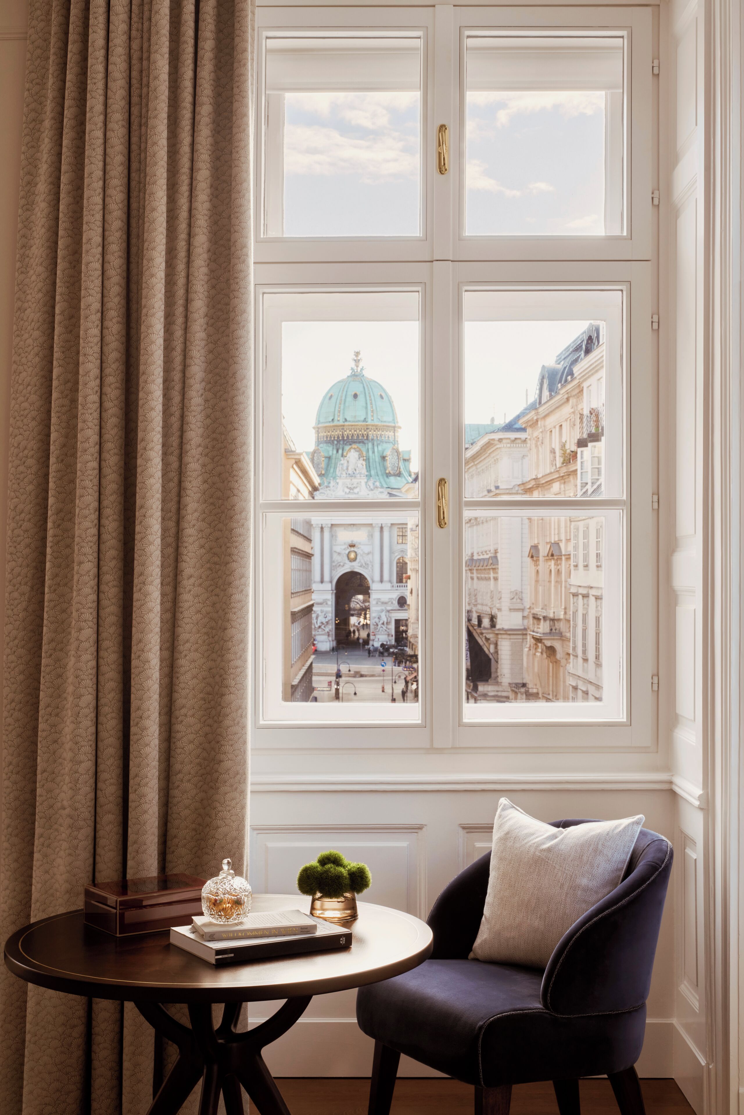 A room with a view of a historic building through a large window with two doors.