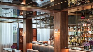 A bar area with wooden accents, bar stools, and a variety of bottles. - Rosewood Vienna (Vienna)