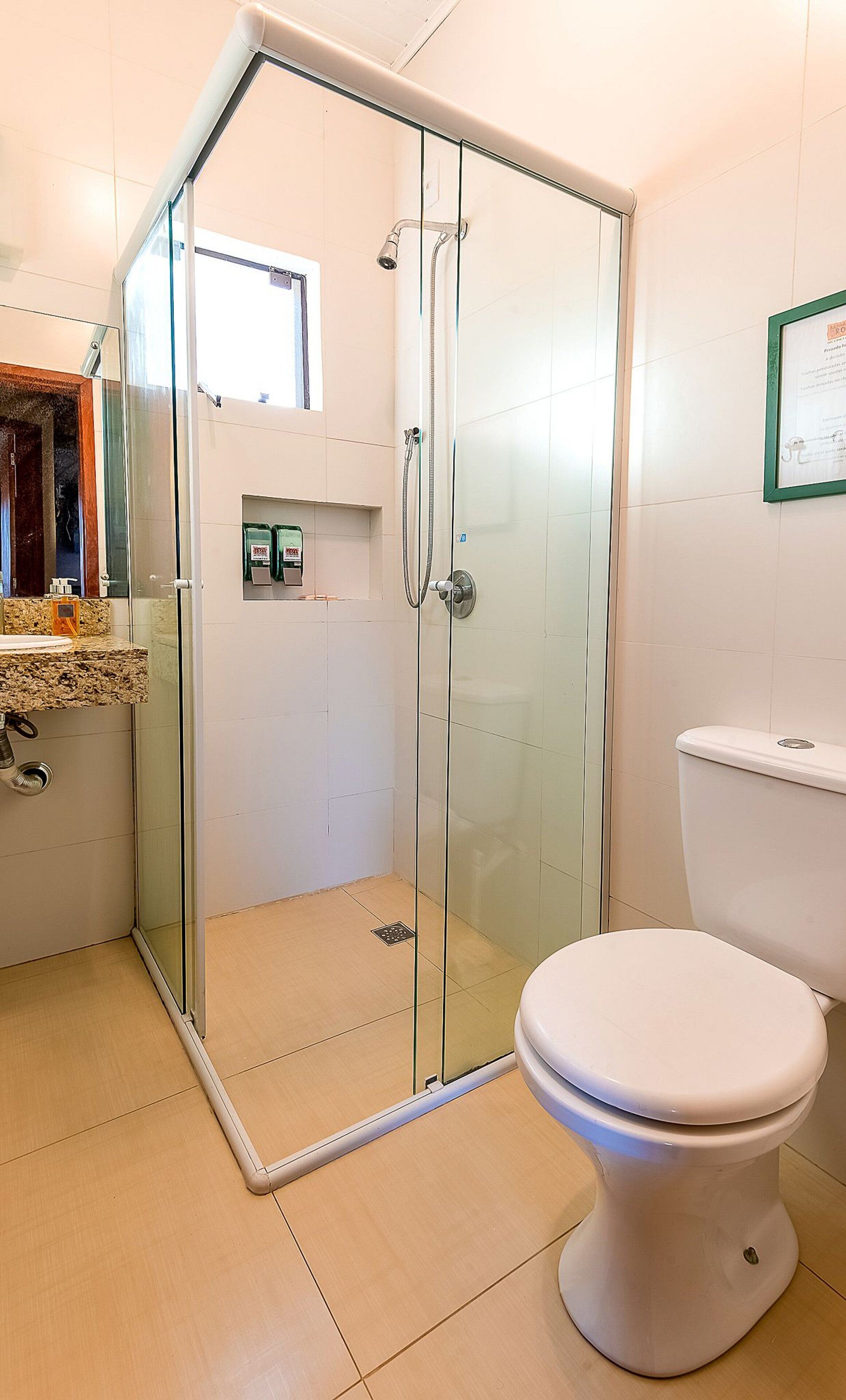A bathroom with a glass shower enclosure, a toilet, and a sink with a granite countertop.