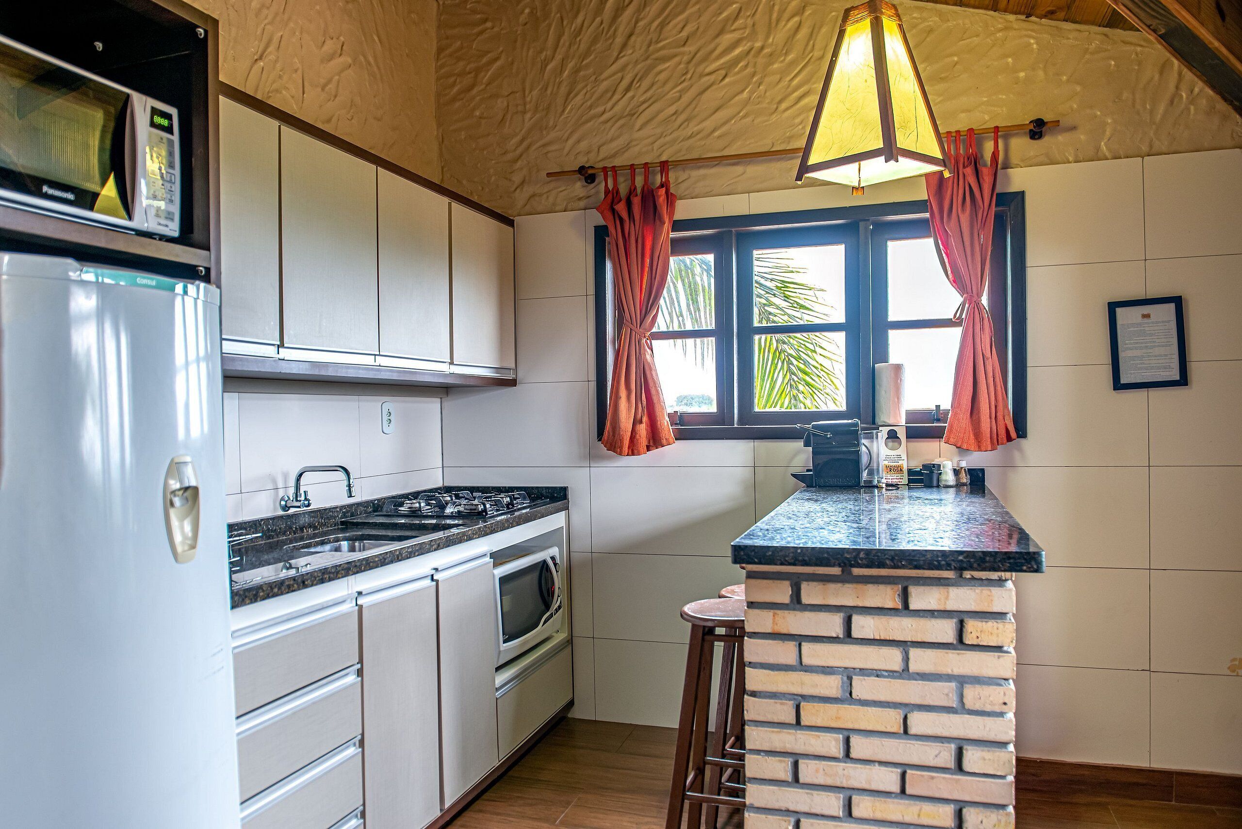 A compact kitchen with white cabinets, a built-in oven, a gas stove, and a brick accent wall.