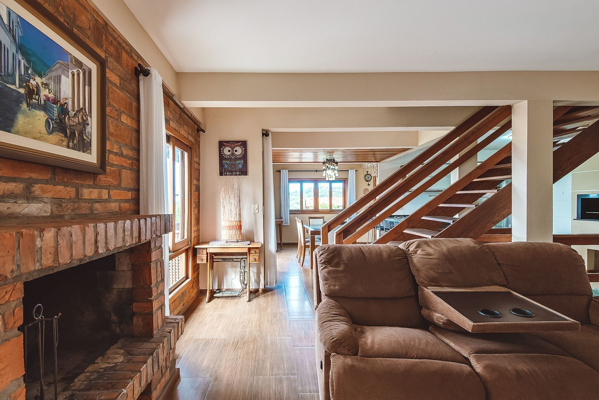 A spacious living area with a brick fireplace, a brown leather sofa, and a dining table with chairs.