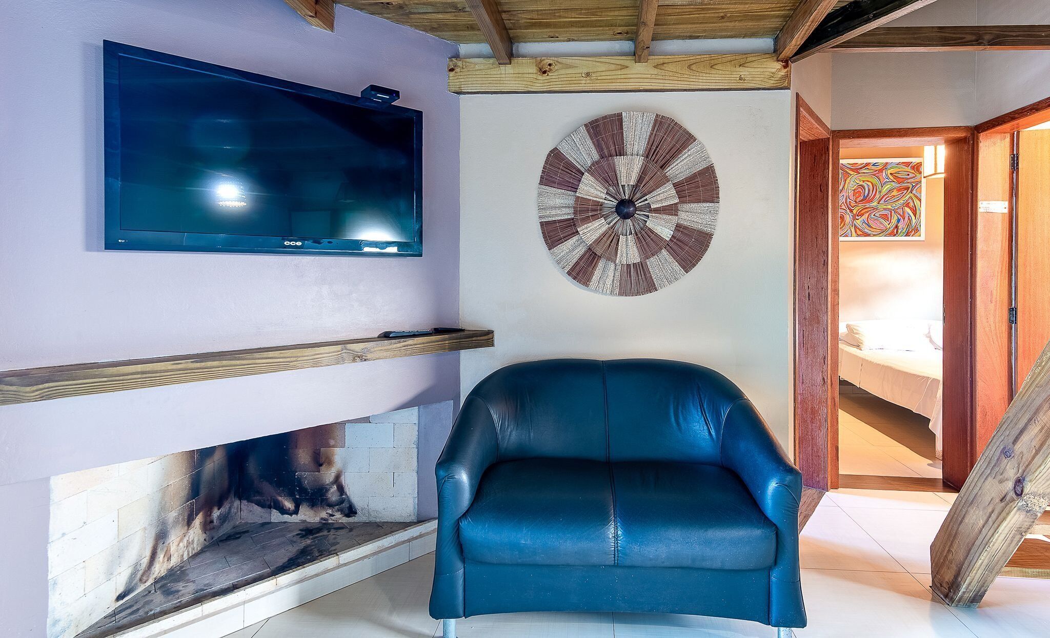 Una sala de estar con televisión, dardo, sillón de cuero azul y chimenea.
