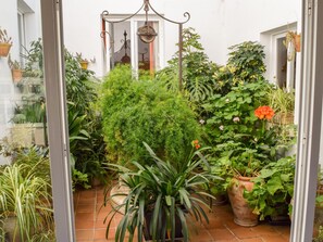 A glass-enclosed patio with various potted plants, a hanging lantern, and a tiled floor.