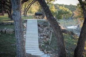 Stairs lead up to a sheltered seating area surrounded by trees and a scenic view.