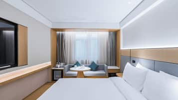 Una habitación de hotel moderna con una cama grande, un área de descanso con una mesa y un televisor.