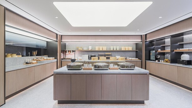 A modern kitchen with a central island, built-in appliances, and a large skylight.