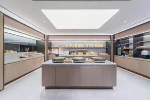 A modern kitchen with a central island, built-in appliances, and a large skylight.