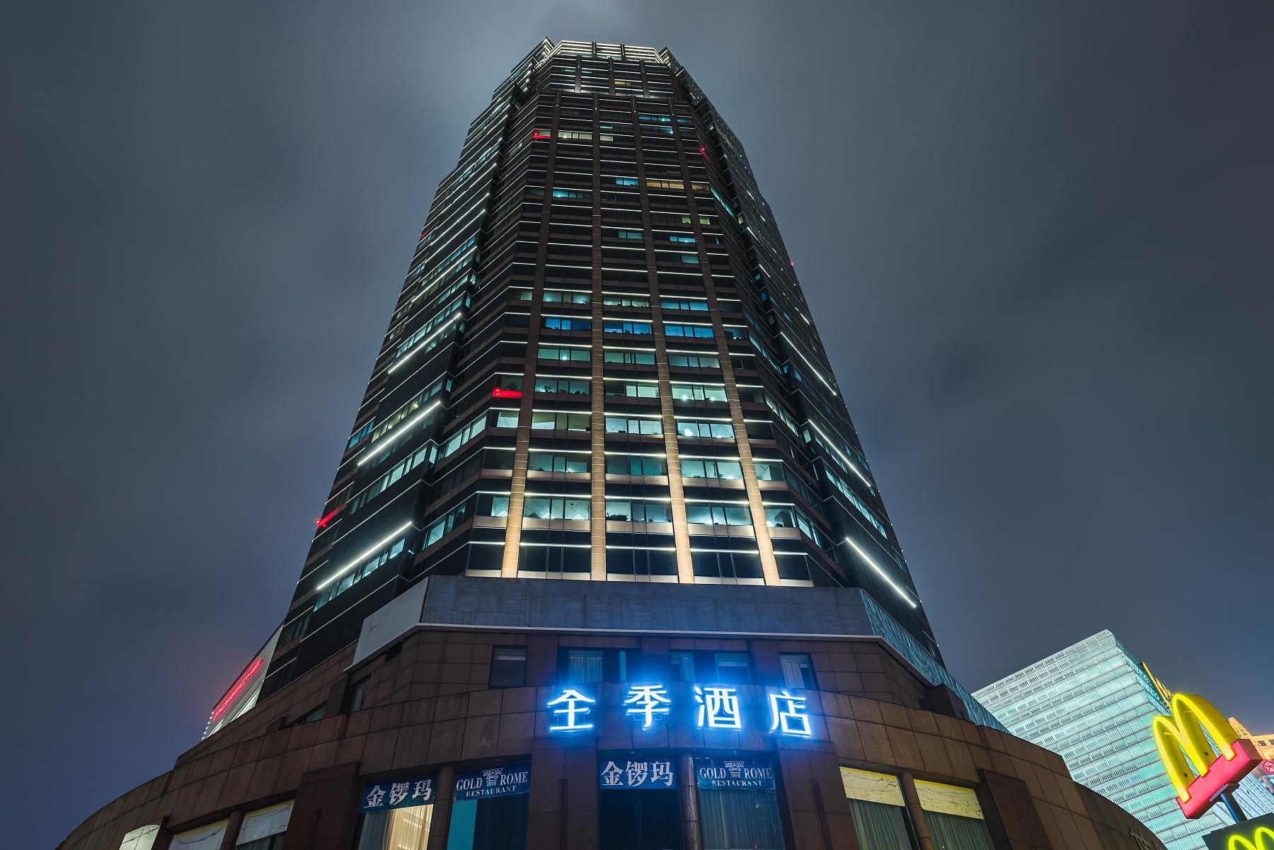 A tall hotel building with illuminated signage, multiple floors, and a modern architectural design.