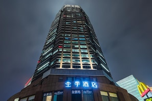 A tall hotel building with illuminated signage, multiple floors, and a modern architectural design. - Ji Hotel (Shanghai)
