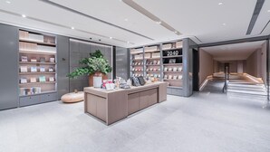 A modern bookstore interior with a central reception desk, bookshelves, and a staircase leading to another level.