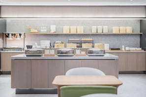 A modern kitchen with a central island, a dining area with chairs, and a counter with food storage containers. - Ji Hotel (Shanghai)