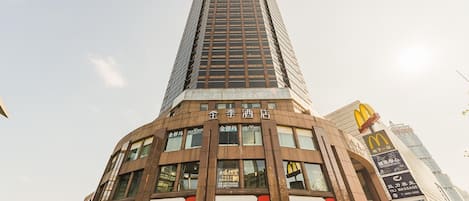 Un grand immeuble orné de nombreuses enseignes, dont « 金陵酒店 » et « 广发银行 CGB ».