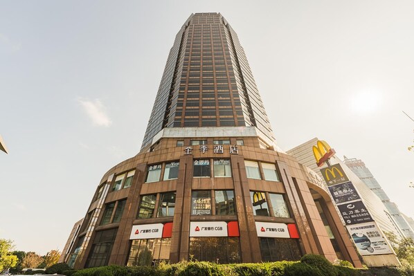 A tall building with multiple signs, including '金陵酒店' and '广发银行 CGB'. - Ji Hotel (Shanghai)