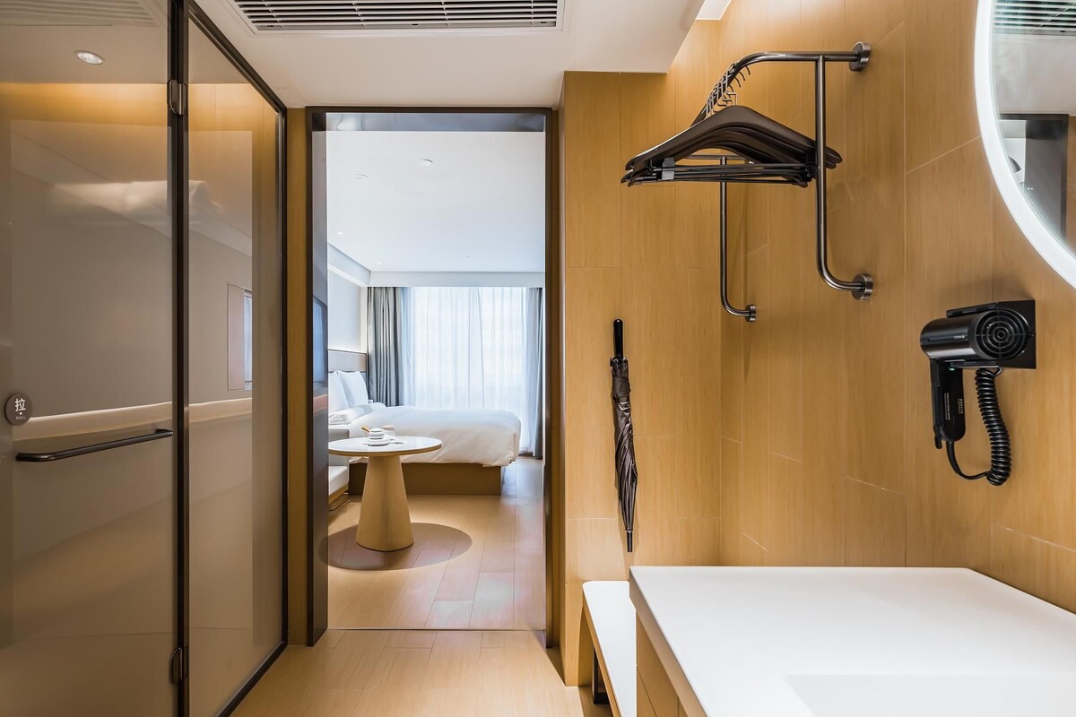 A modern hotel bathroom with a shower, a hairdryer, and a towel rack.