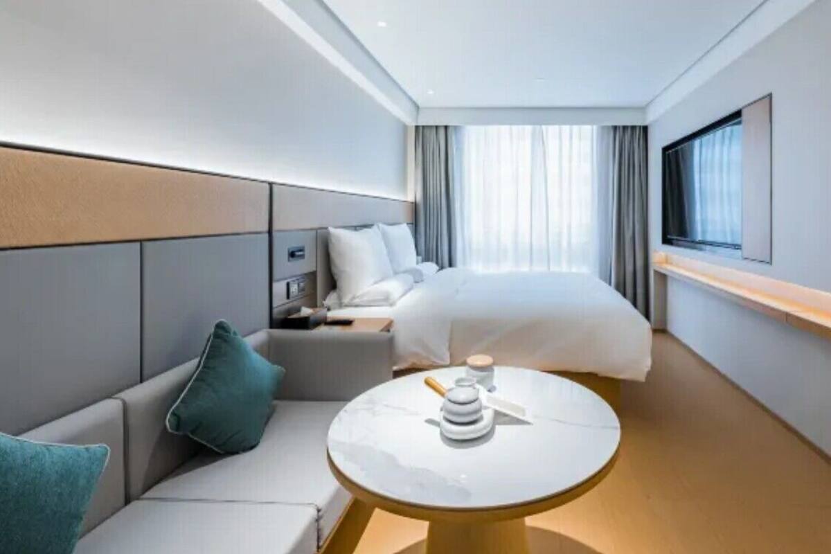 Une chambre d’hôtel moderne équipée d’un lit, d’un canapé, d’une petite table et d’un téléviseur.