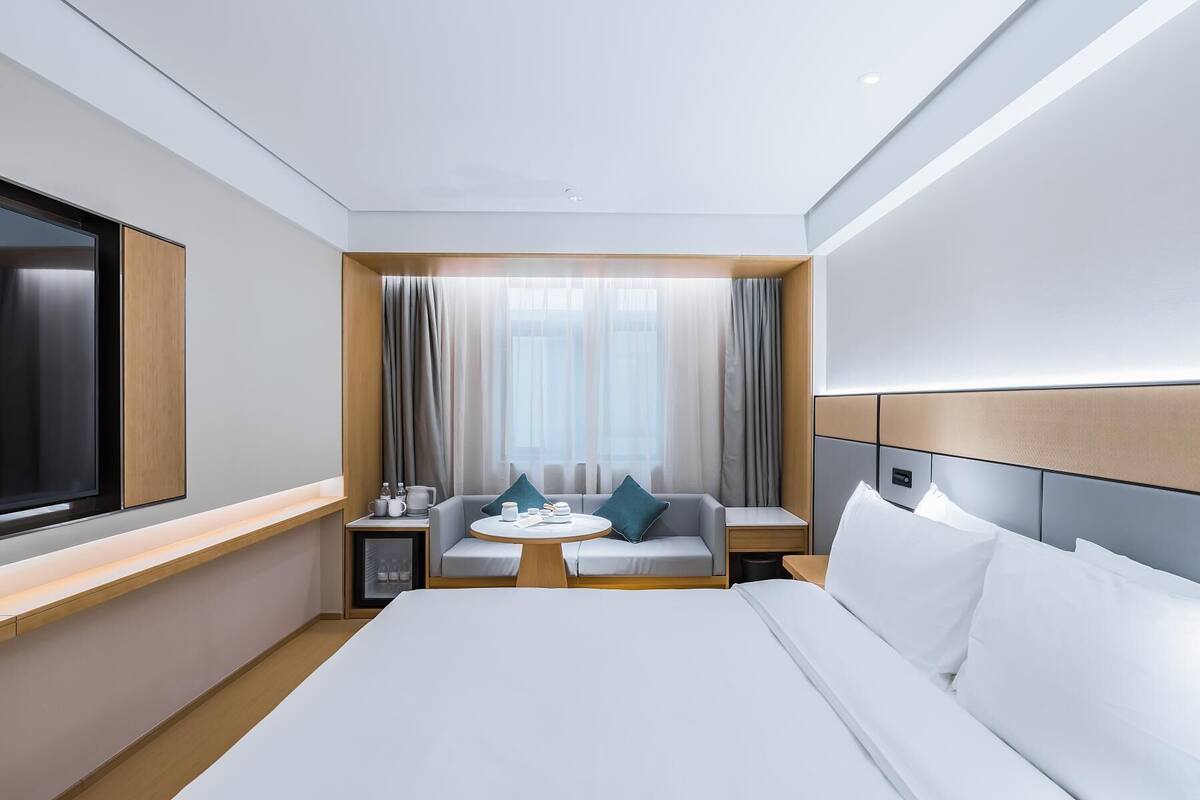 Une chambre d’hôtel moderne avec un grand lit, un coin salon avec une table et un téléviseur.
