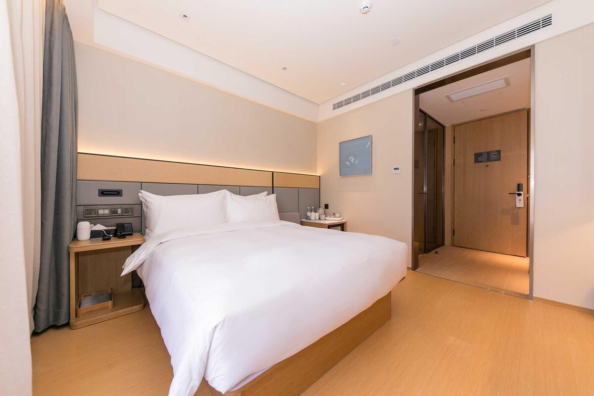 A hotel room with a bed, bedside table, and a door to the bathroom.
