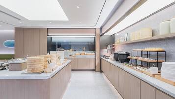 Una cocina moderna con una isla central, vistas al área de comedor y un mostrador con diversos alimentos.