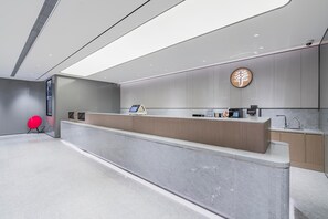 A modern reception desk with a digital display, a sink, and a wall-mounted sign. - Ji Hotel (Shanghai)